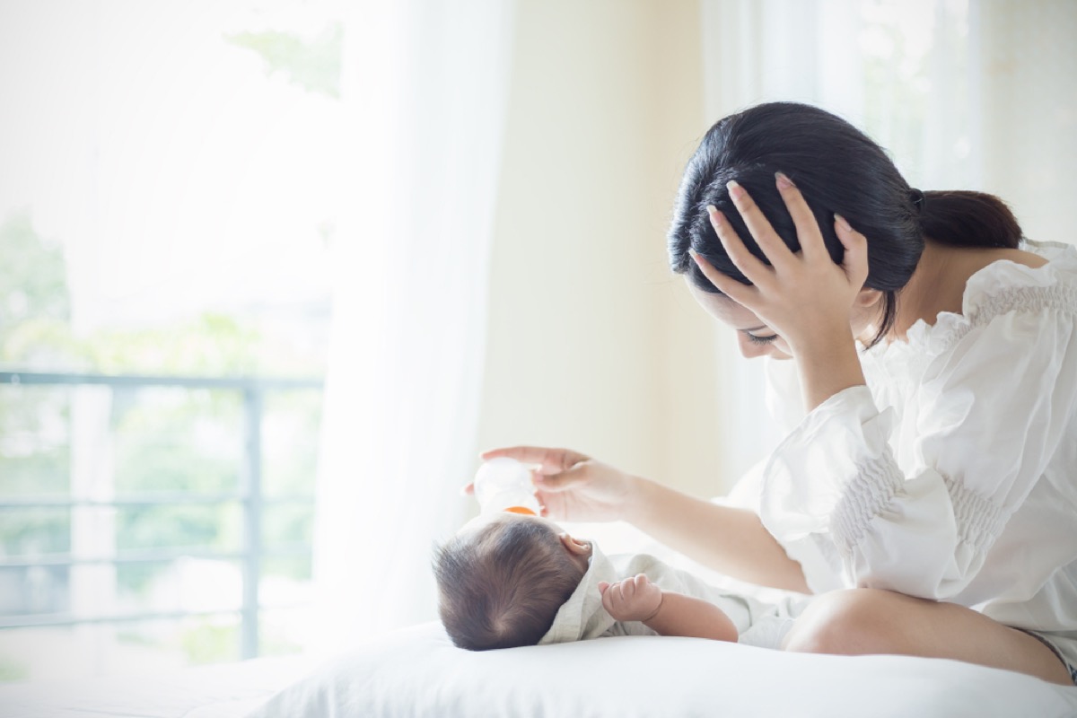 woman looking depressed while feeding baby, working mom