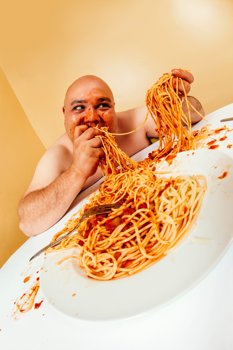 Overweight Man Eating Spaghetti With His Hands Funny Stock Photos