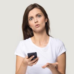 woman holding phone and looking confused