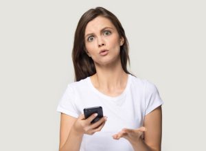 white woman holding phone and looking confused