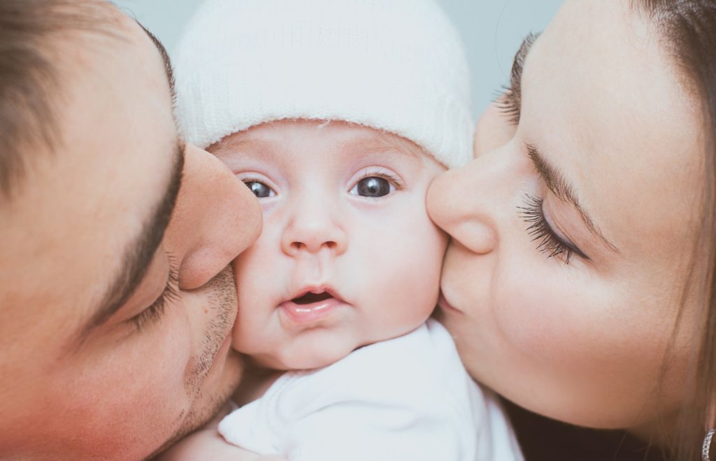 parents kissing baby, how parenting has changed