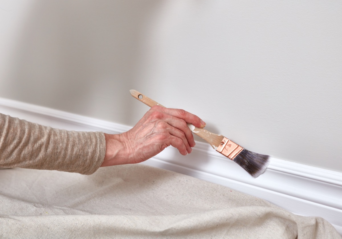 old woman painting the molding in her home