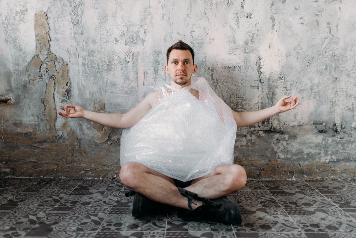 Man Practicing Yoga in a Basement Wearing a Plastic Bag Funny Stock Photos