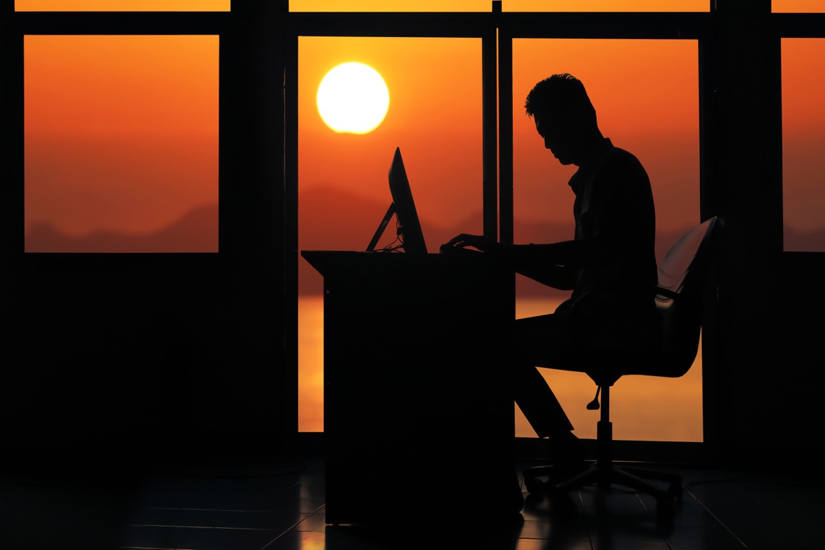 silhouette of man in office working at desk as sun rises, married for money