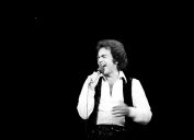 Neil Diamond performs in white wide collar shirt and black vest