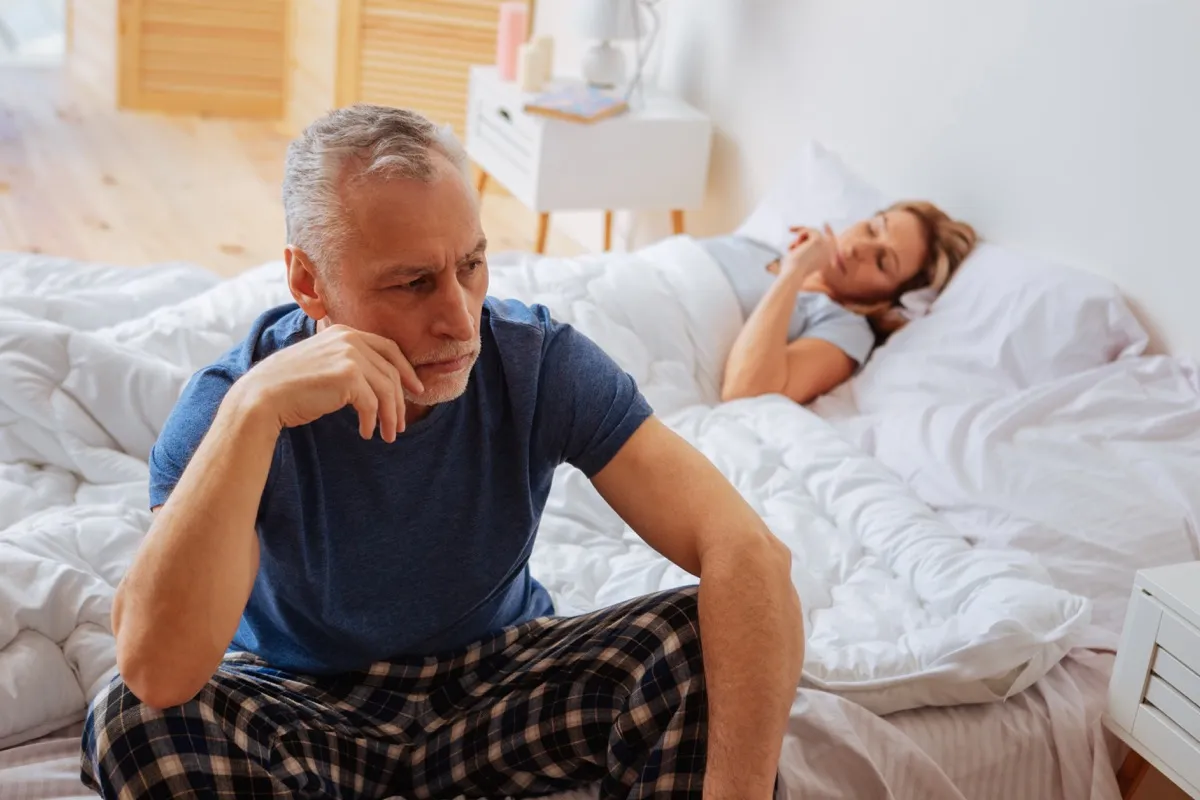 angry couple laying in bed, health questions over 40