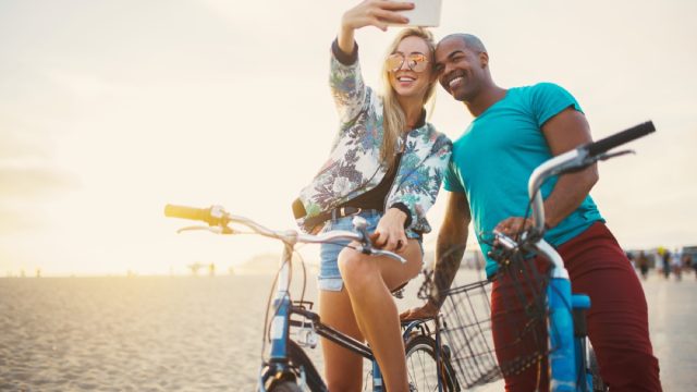 attractive interracial couple on bikes taking selfie, make yourself more attractive