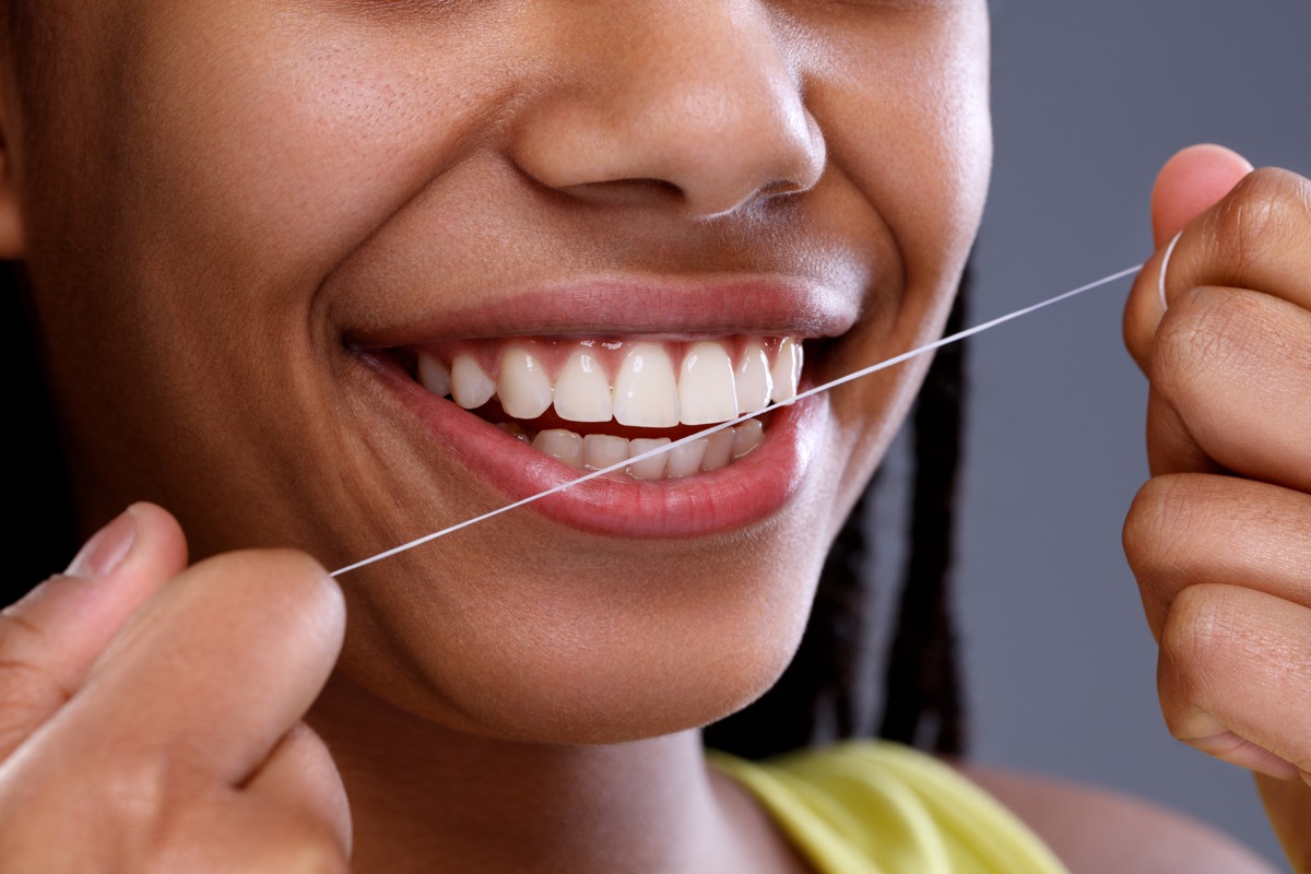 Black Woman Smiling and Flossing, subtle symptoms of serious disease