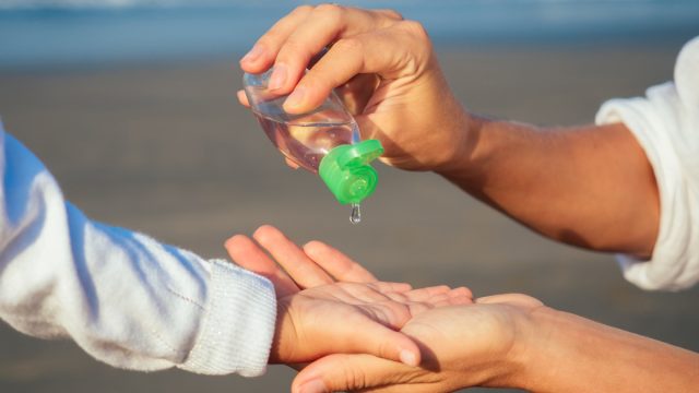 Mom Giving Her Child Hand Sanitizer on the Beach bad parenting