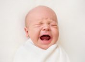 crying newborn baby in swaddle, parenting tips