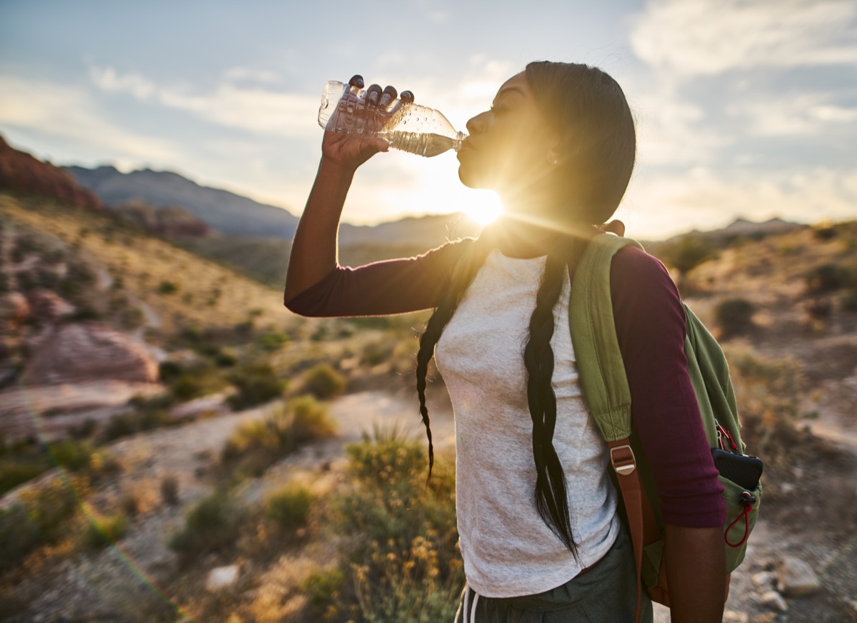 girl drinking from a water bottle after a walk or hiking, aging quicker