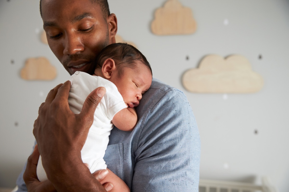 black father holding newborn baby on chest