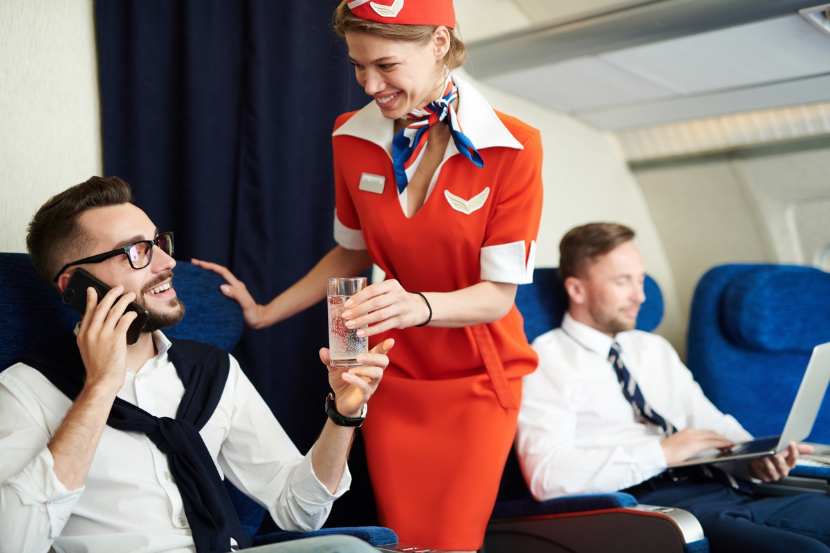 flight attendant talking to man on airplane