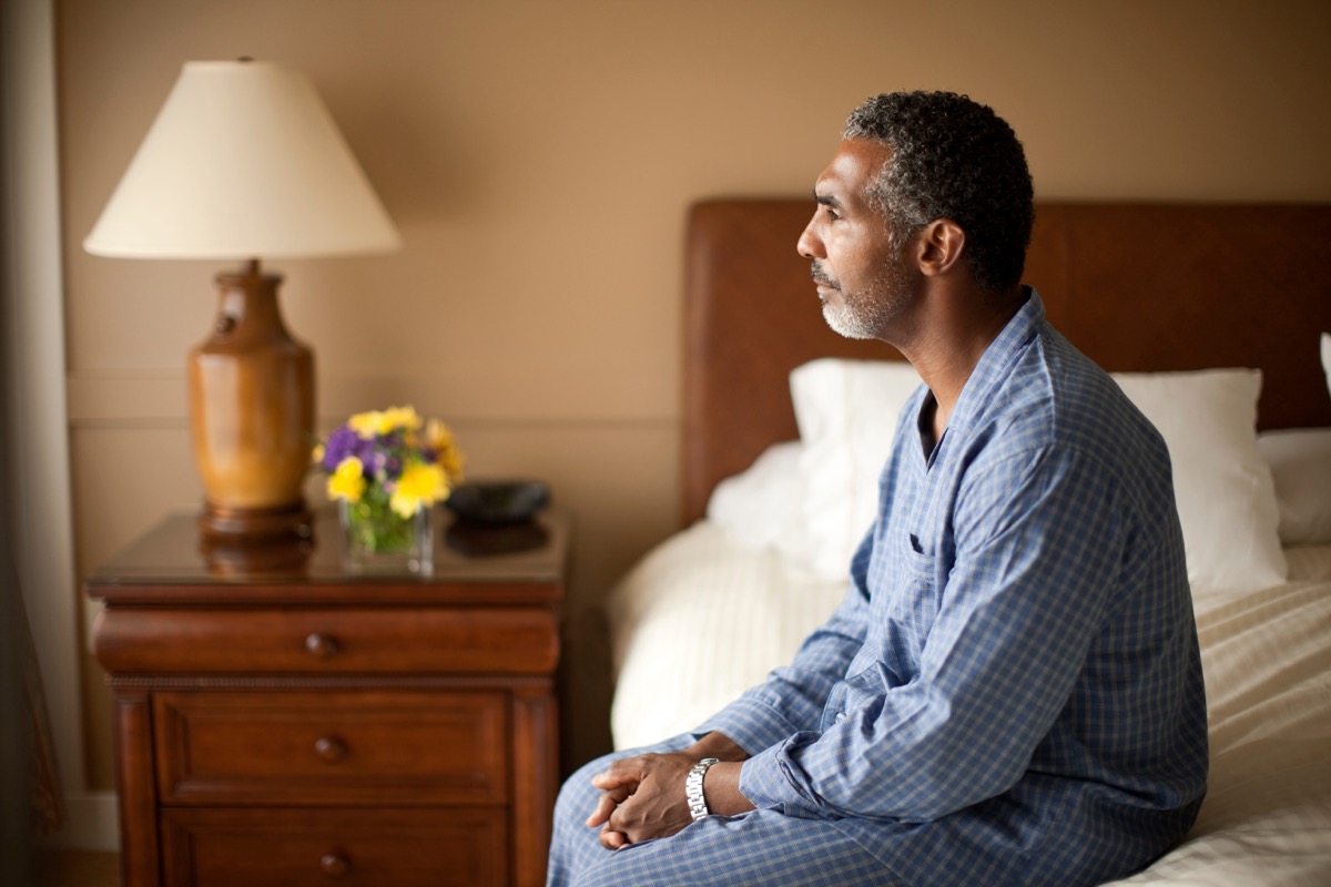 man sitting on bed can't sleep, over 50 fitness