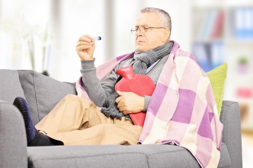 Older man sick on the couch with a fever