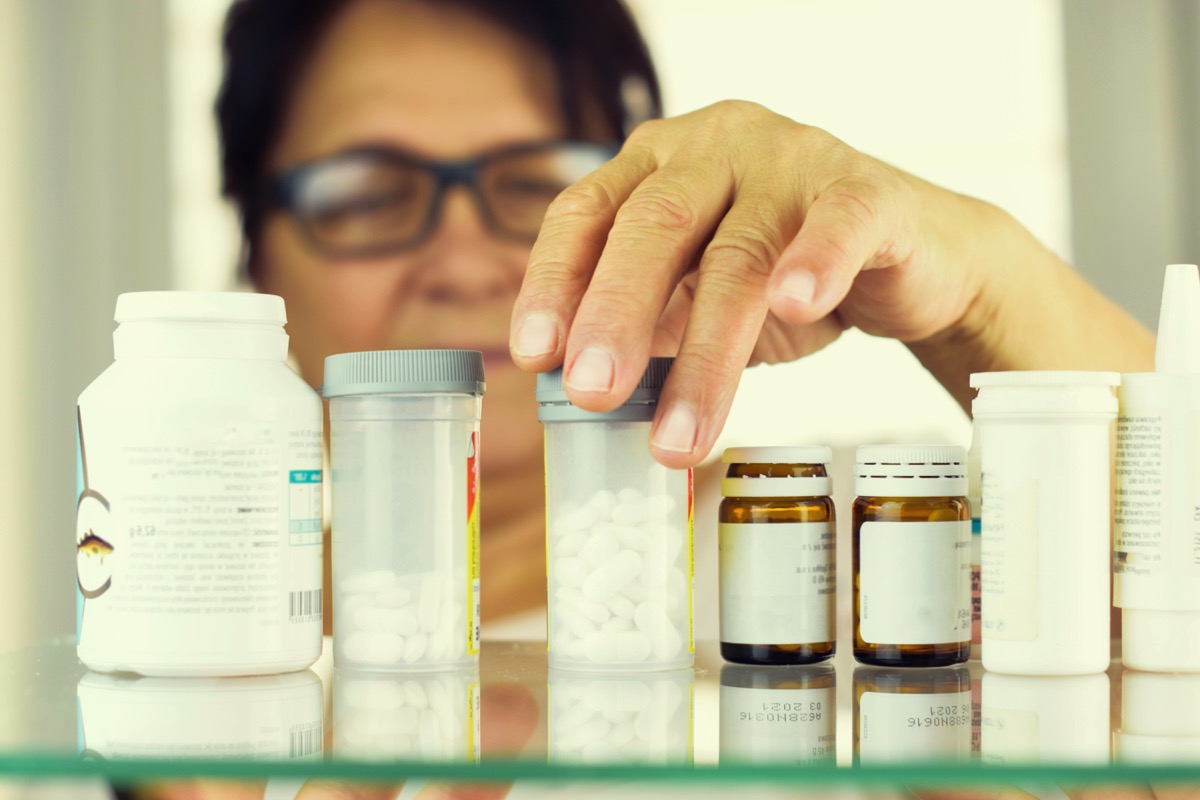 woman looking through her medications in her medicine cabinet, things you should never store in your attic