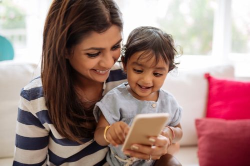 woman holding baby and cell phone, reach a customer service rep