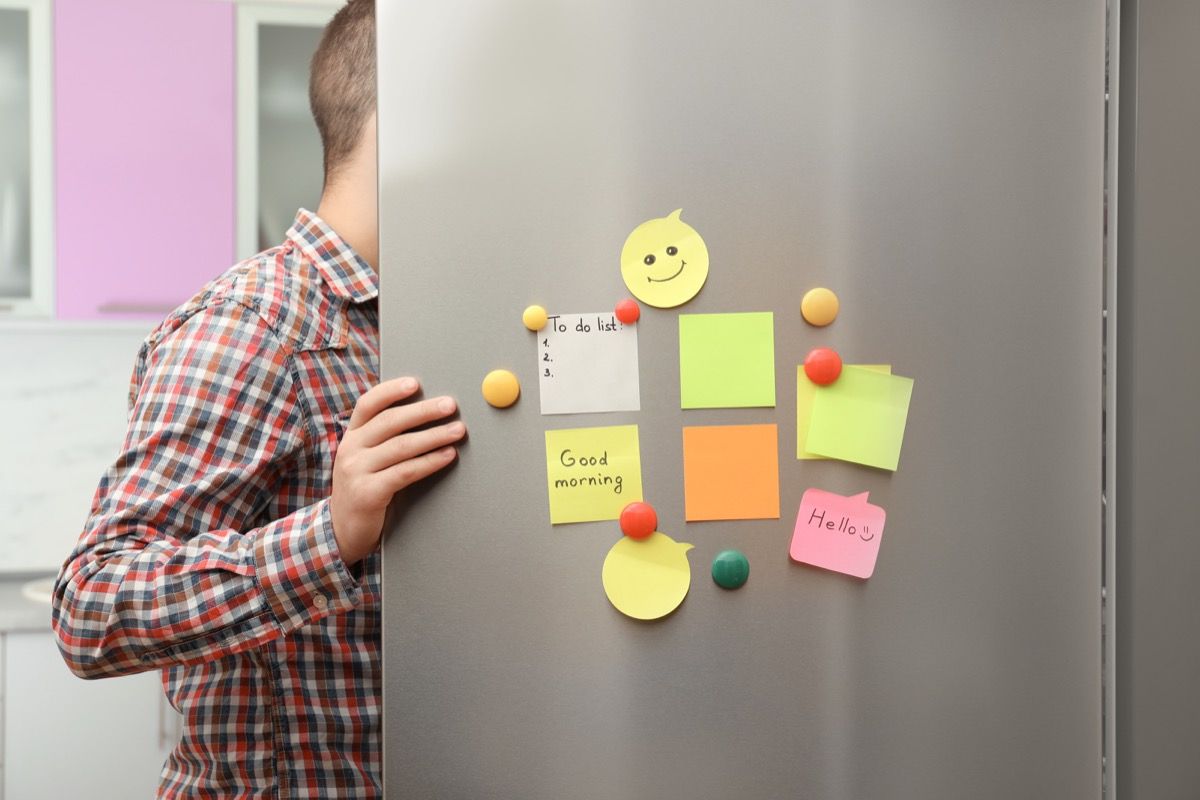 man opening fridge door with note on it