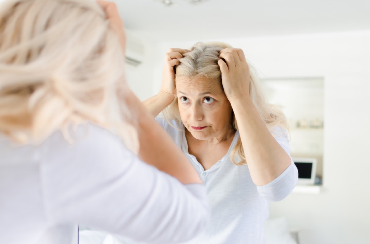 older woman looking at hair in mirror, look better after 40