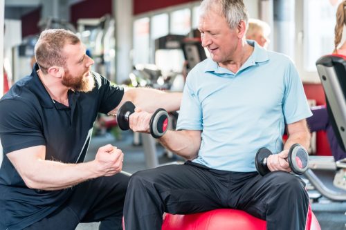 personal trainer helping older man exercising, over 50 fitness