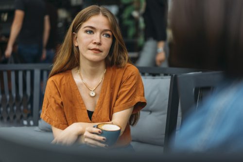 Concerned young woman talks with friend in coffee shop