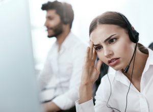 young female customer service rep looks annoyed while using headset, things never to say to customer service rep