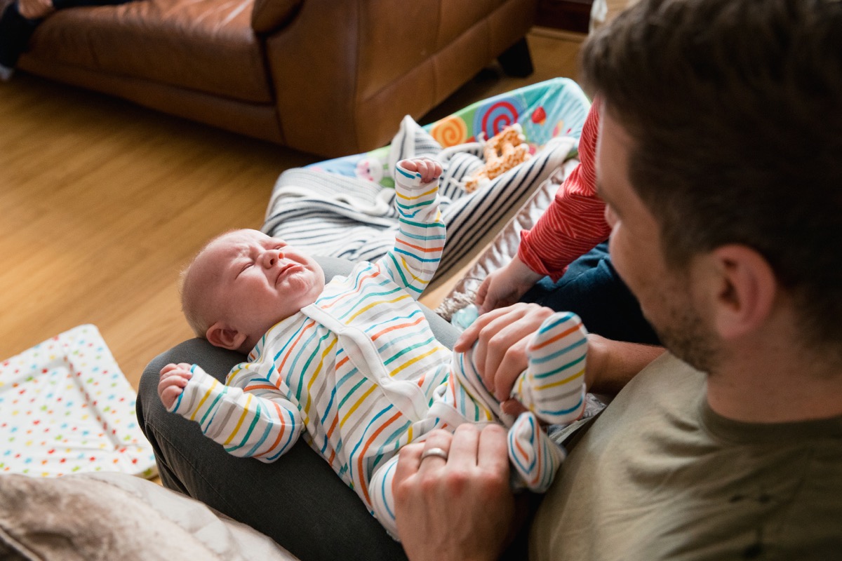 Closeup of dad holding infant in lap, stay-at-home dad