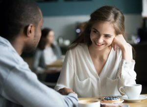Young woman smiling at man at coffee shop