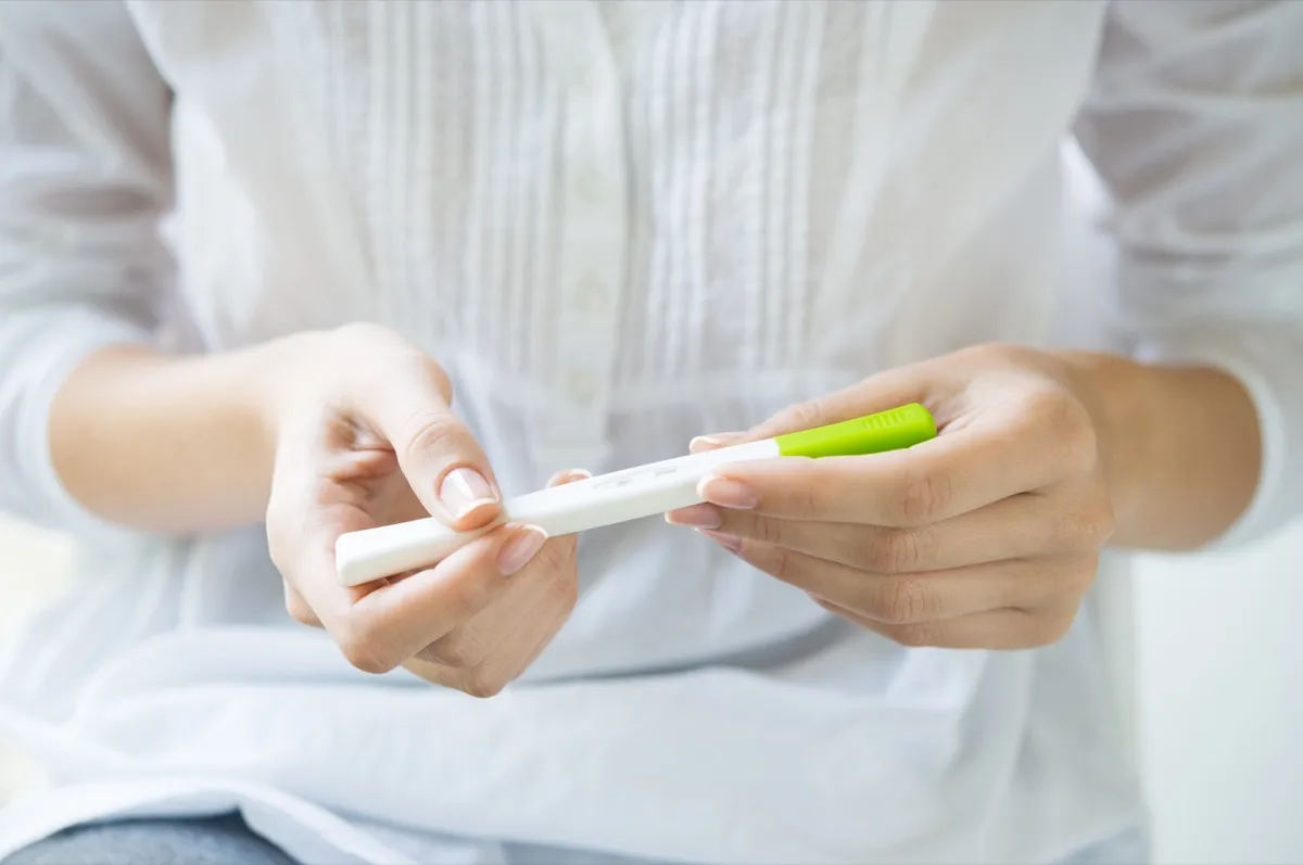 Woman holds pregnancy test in hands, what it's like being a teen mom