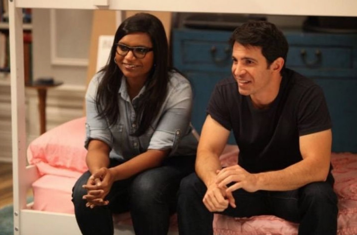 Mindy and Danny sitting on a bed