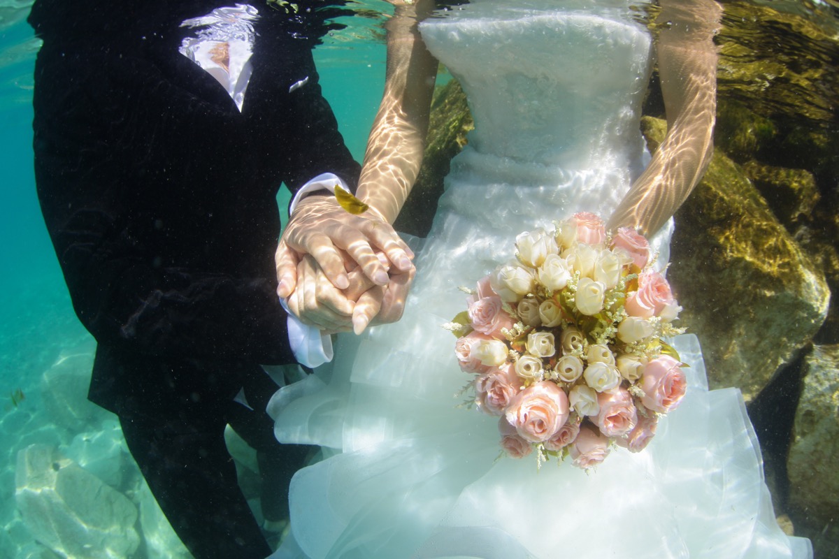 groom and bride hold hands underwater, craziest things brides and grooms have ever done at weddings