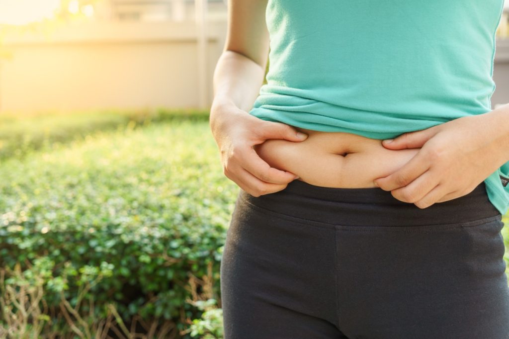 woman outside squeezing belly fat