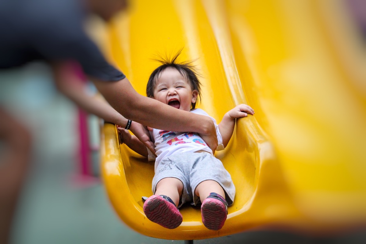 parent helping child down a slide