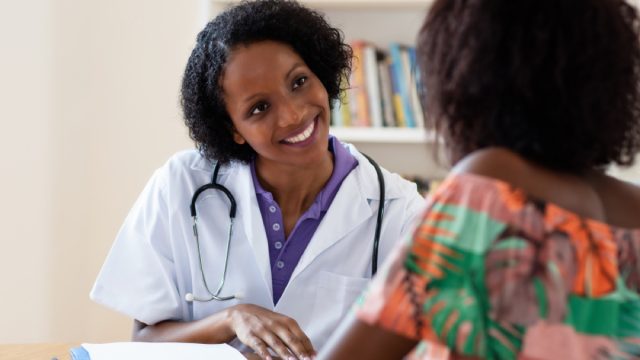 young black doctor talking to female patient, skin cancer facts