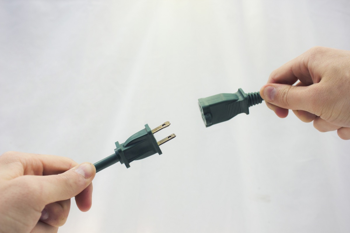 white hands plugging two green cords into one another