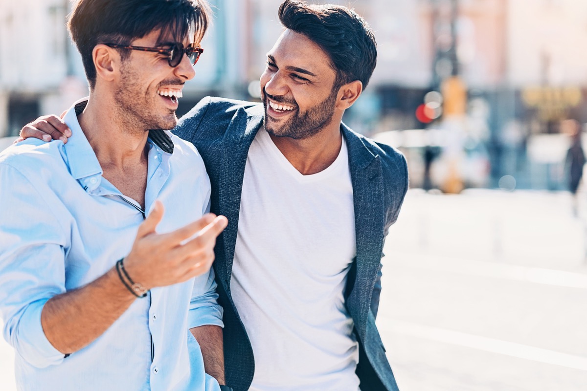 two young indian men laughing together on the street