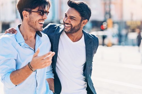two young indian men laughing together on the street