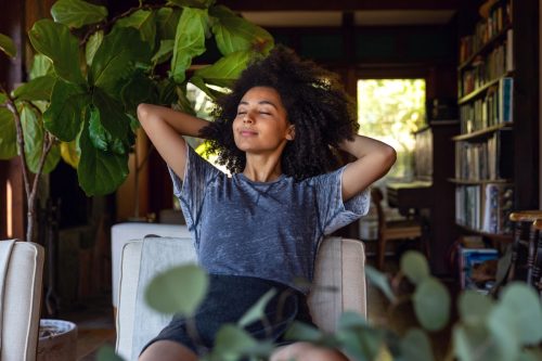 young black woman relaxing with her eyes closed in a chair inside