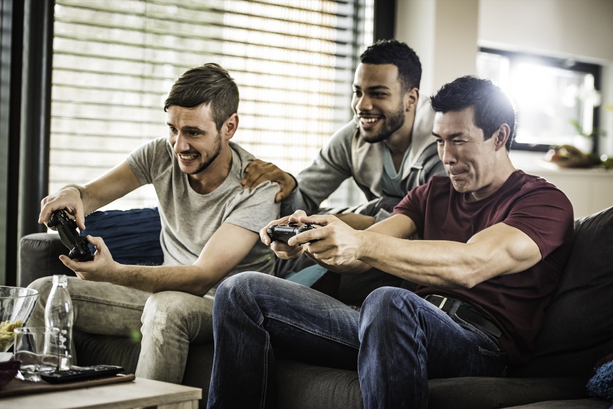 young white man black man and asian man playing video games