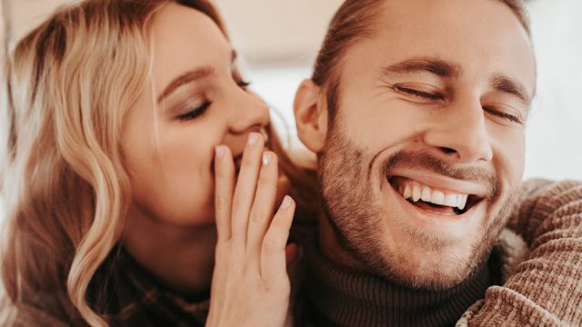 white woman whispering to laughing white man