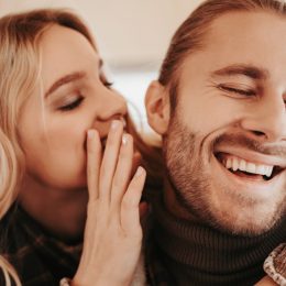 white woman whispering to laughing white man