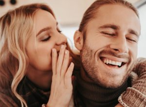 white woman whispering to laughing white man