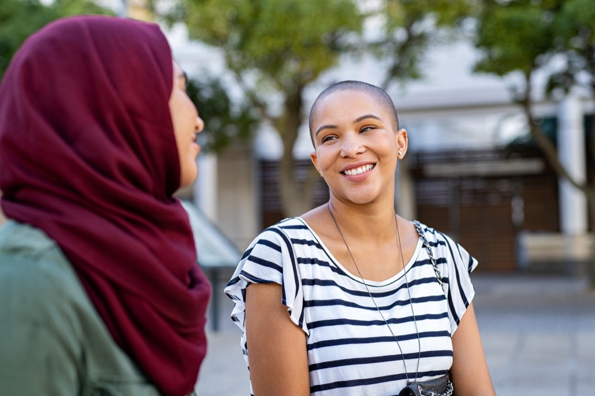 young woman smiling and talking to another woman in a hijab