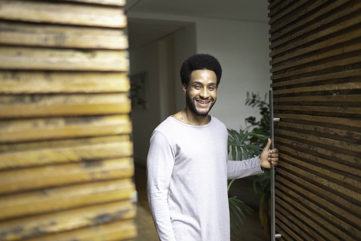 black man opening the door to his home and smiling