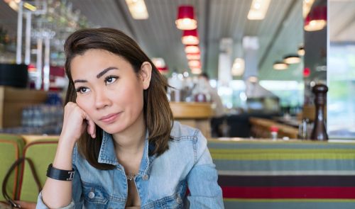 jovem mulher asiática olhando irritada e revirando os olhos para um restaurante