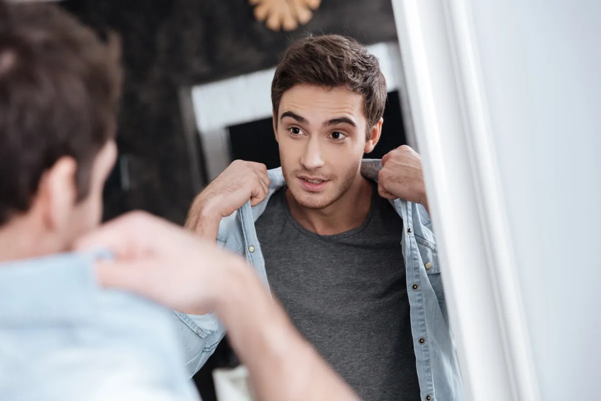 man looking at his clothes in the mirror, relationship white lies