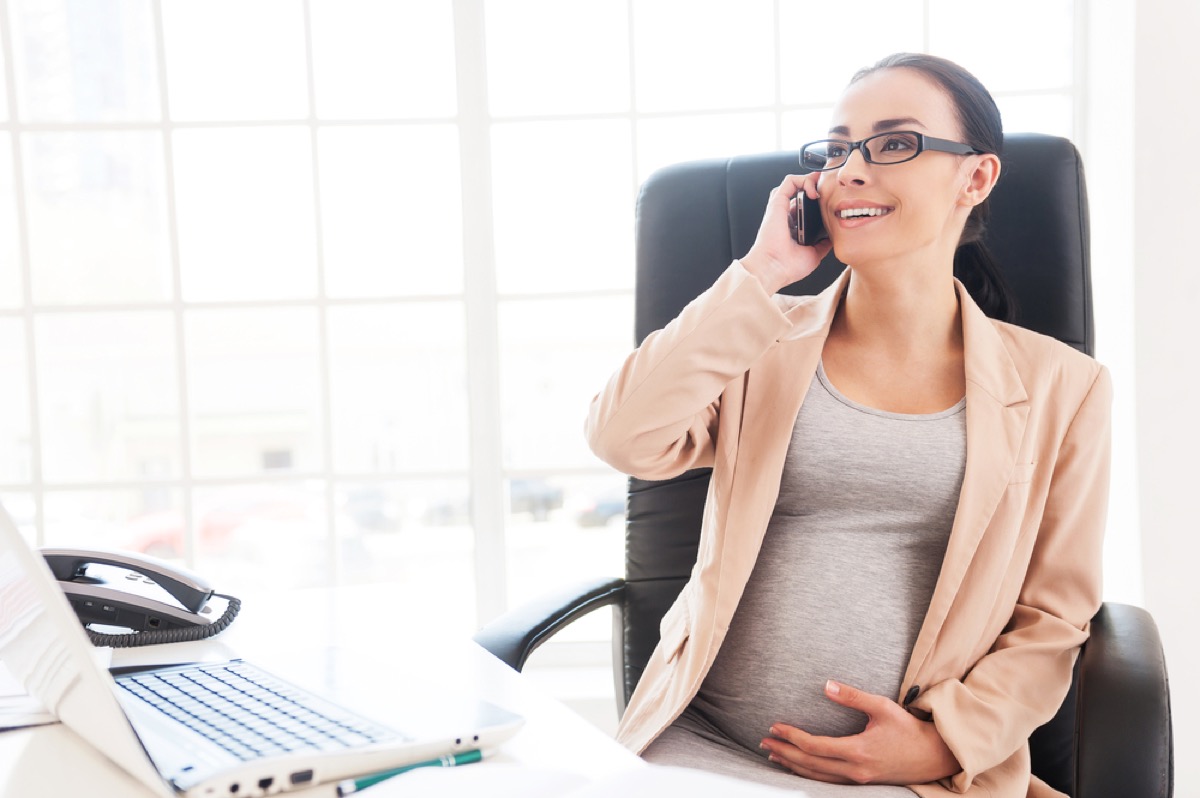 pregnant woman on the phone at her desk, office etiquette