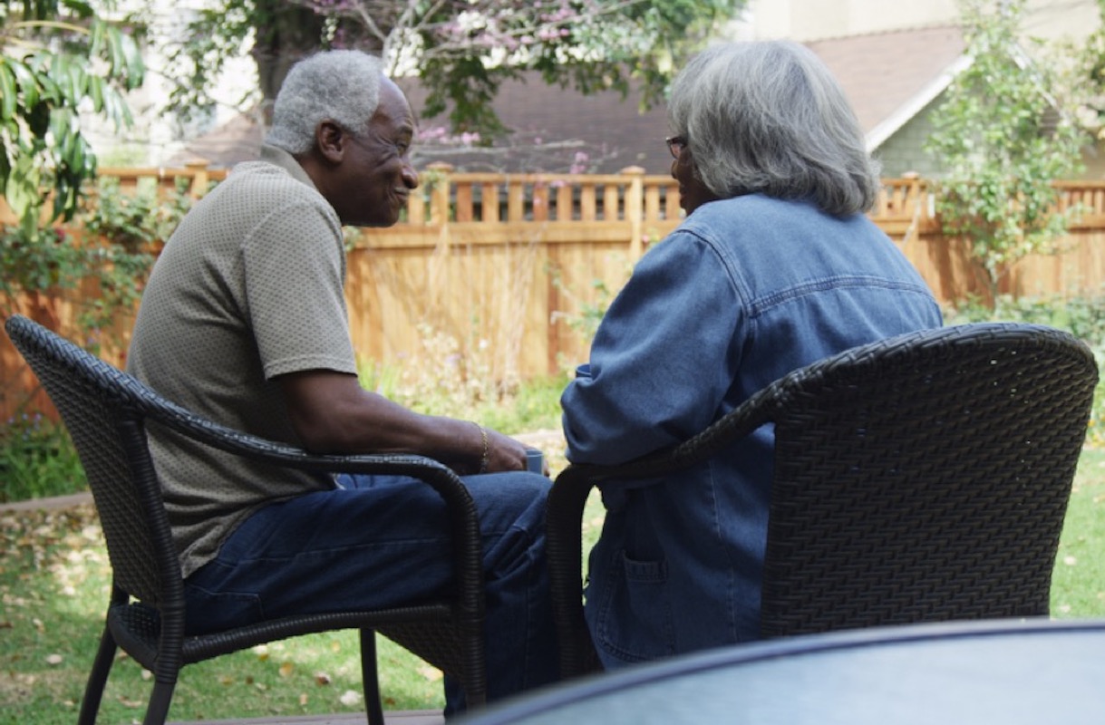 senior black couple talks outside in backyard