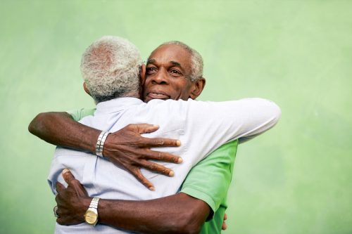Two senior black men hugging outdoors