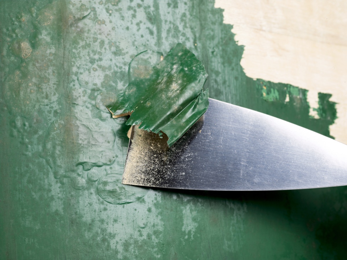 stripping green paint with metal scraper
